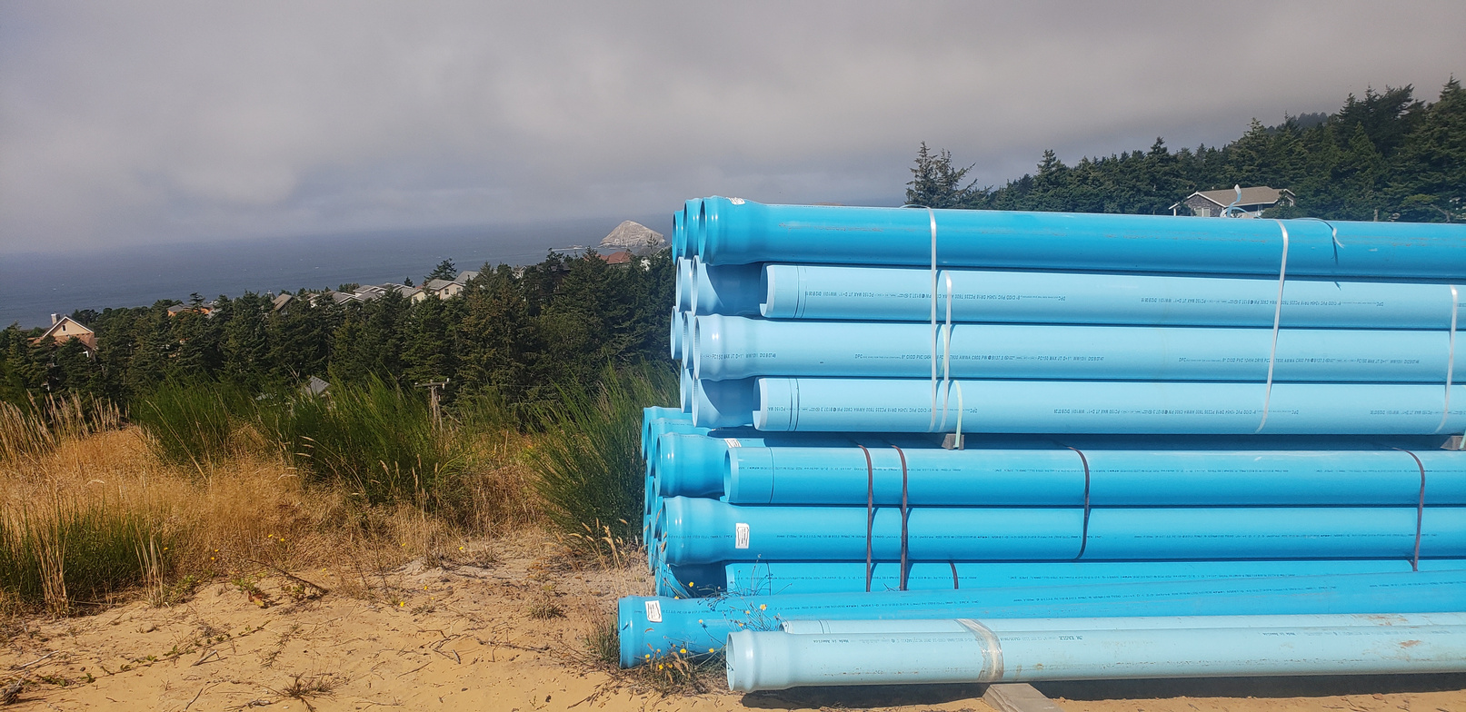 Blue waterline pipe staged above an Oregon coastal community